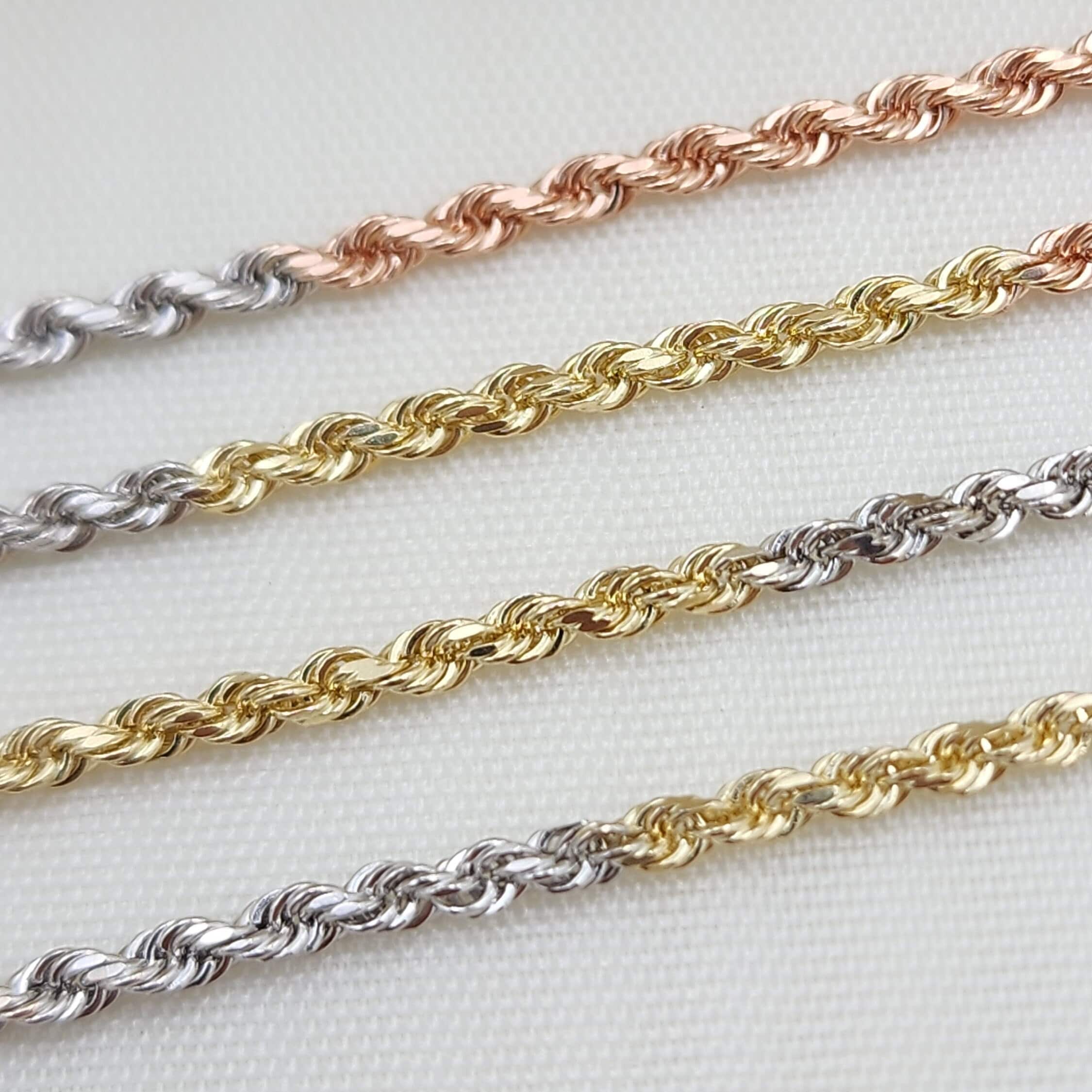 May include: Three gold rope chains, one in rose gold, one in yellow gold, and one in white gold. The chains are laid out on a white surface.