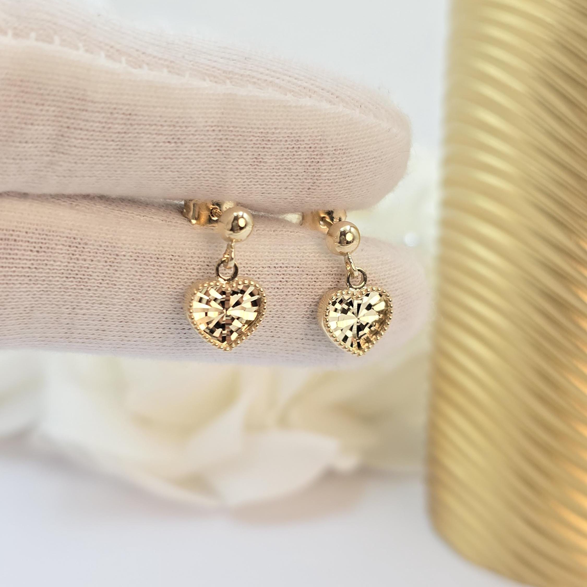 May include: A pair of gold heart shaped earrings with a textured surface.