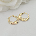 May include: Close-up of a pair of gold hoop earrings. The hoops are adorned with small, heart-shaped details in three-toned gold: yellow, white, and rose. The earrings have a smooth, curved design and are displayed against a white background.