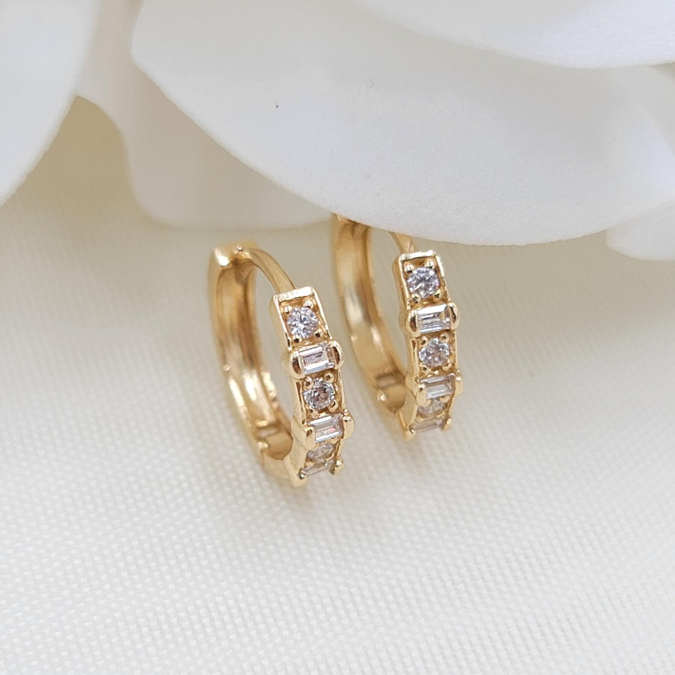 May include: Two gold hoop earrings with a row of clear cubic zirconia stones set in the hoop.