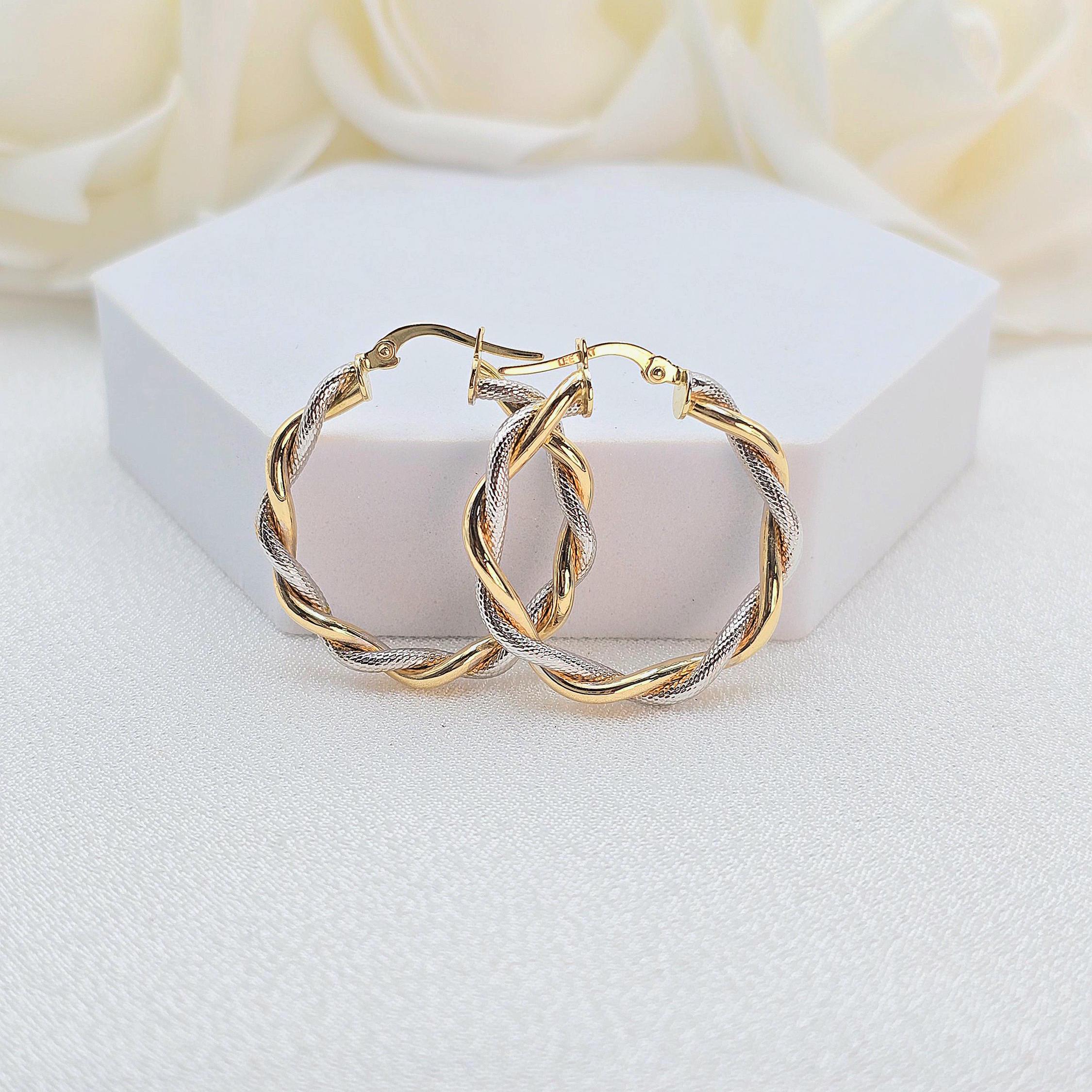 May include: Two gold and silver hoop earrings with a twisted design.